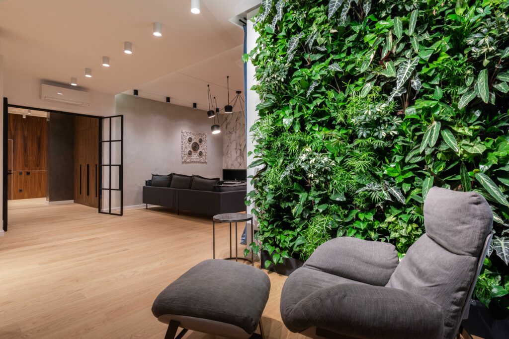 pexels-photo-6585744-6585744 Interior of light modern flat with armchair with pouf near green wall with plants leaves
